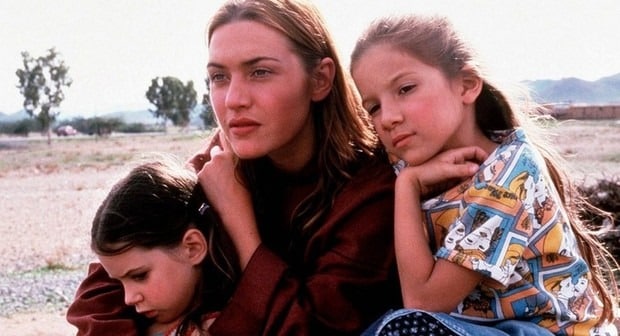 Three children sitting outdoors together.